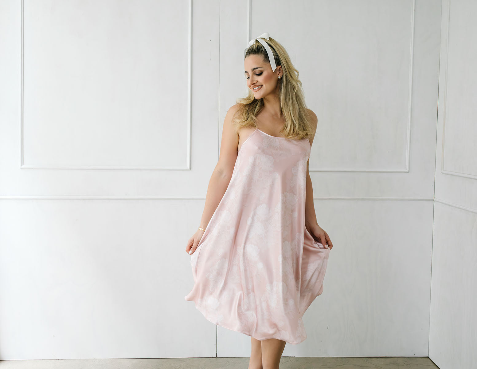 Woman wearing a light pink strapless dress against a white background