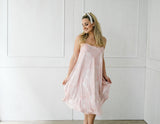 Woman wearing a light pink strapless dress against a white background