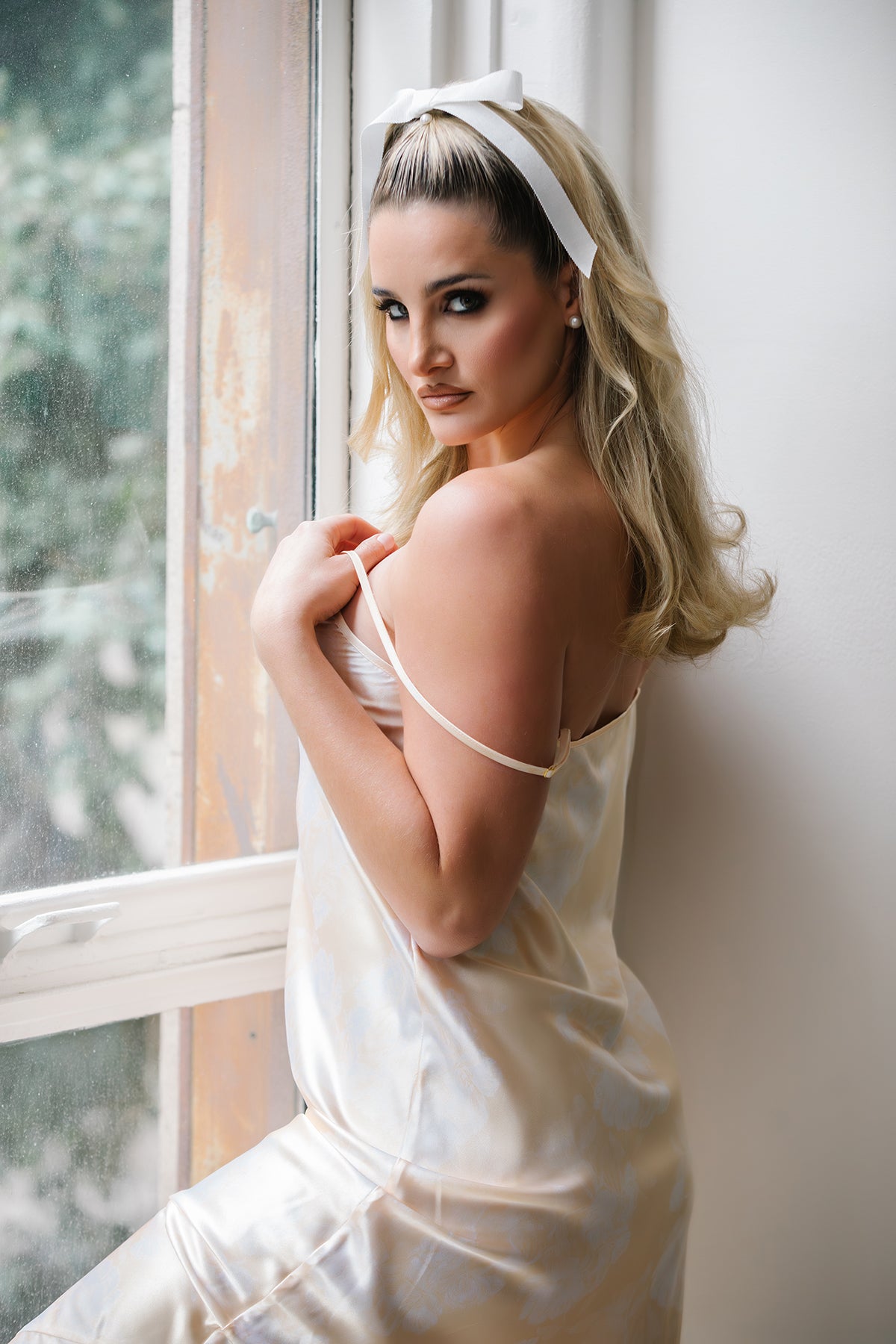 Woman in a white dress standing by a window
