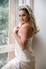 Woman in a white dress standing by a window