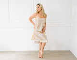 Woman wearing a beige slip dress against a white background
