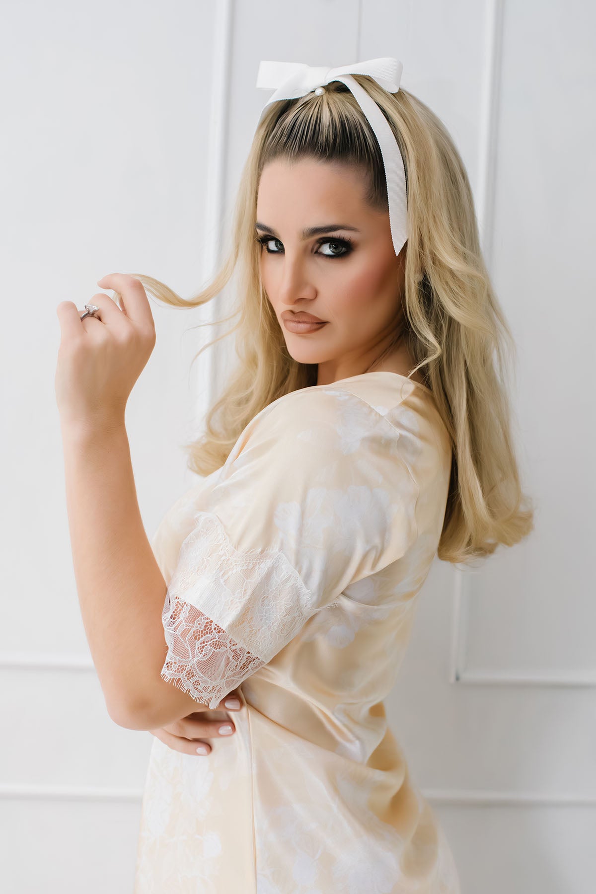 Woman in a white lace dress with a white headband against a white background