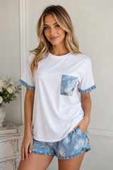 Woman wearing a white t-shirt with blue floral details and matching shorts in a room setting.