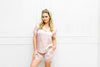 Woman wearing a pink satin pajama set against a white background