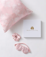 Pink pillow, scrunchie, and eye mask with 'Madeleine Fig' packaging on a white background