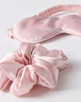 Pink satin eye mask and scrunchie on a white background