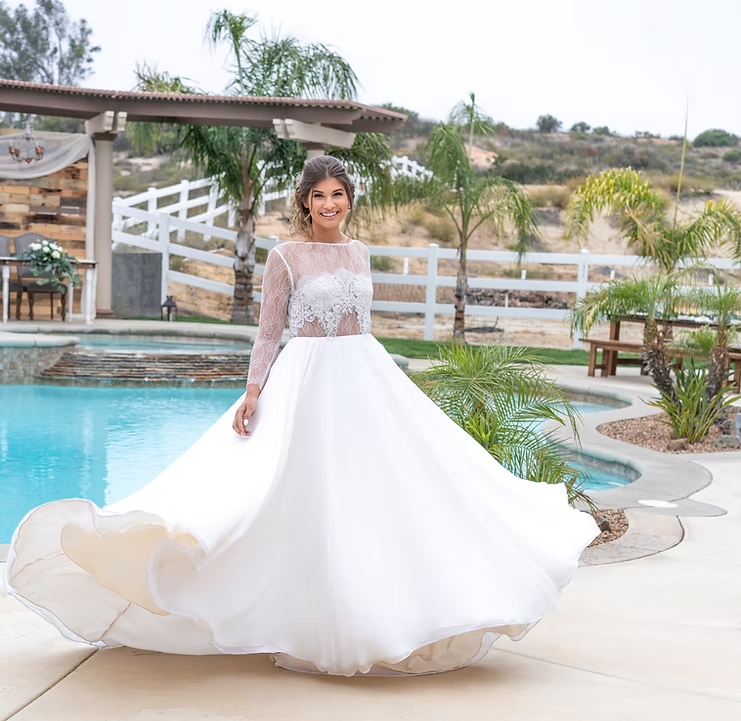Woman in a white wedding dress standing by a pool with a scenic background