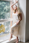 Woman in a white dress standing by a window with 'Madeleine' branding.