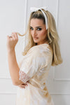 Woman in a white lace dress with a white headband against a white background