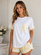 Woman wearing a white and yellow outfit with a pocket detail in a room setting.
