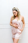 Woman wearing a pink satin pajama set against a white background